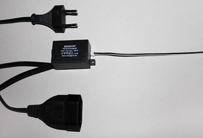 Ein schwarzes Netzteil mit einem Stecker, der an einer Wanddose angeschlossen ist.